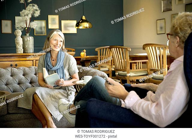 Smiling senior woman sitting on couch in lounge room looking at husband