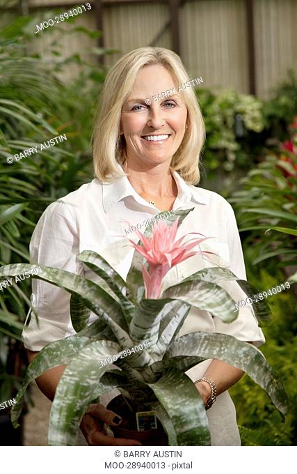 Portrait of a happy senior blond woman in botanical garden