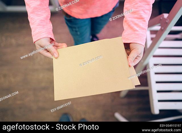 Little girl holding blank banner. Child showing paper sheet for sales advertisement, copy space. Commercial ad mockup