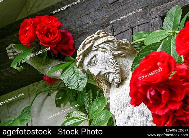 Detail eines mit Rosen überwucherten Holzkreuzes in Oberbayern