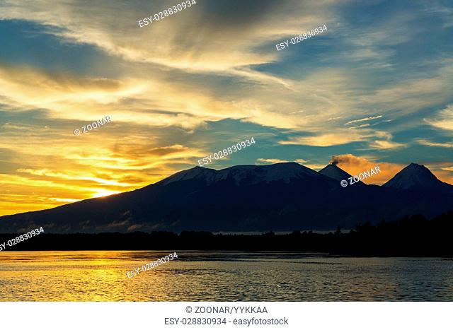 Beautiful sunrise over volcanoes Kluchevskaya group with reflection in the river Kamchatka