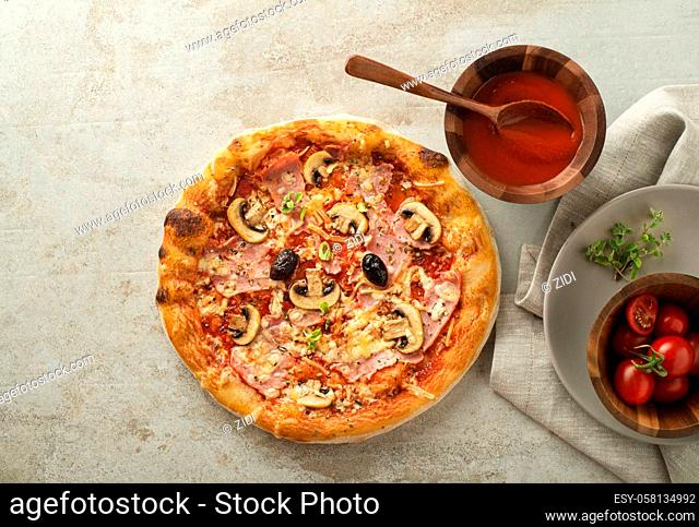 Pizza served with cheese, ham, mushrooms, olives and tomato sauce