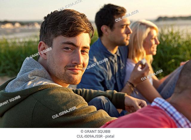 Four adult friends sitting on Bournemouth beach, Dorset, UK