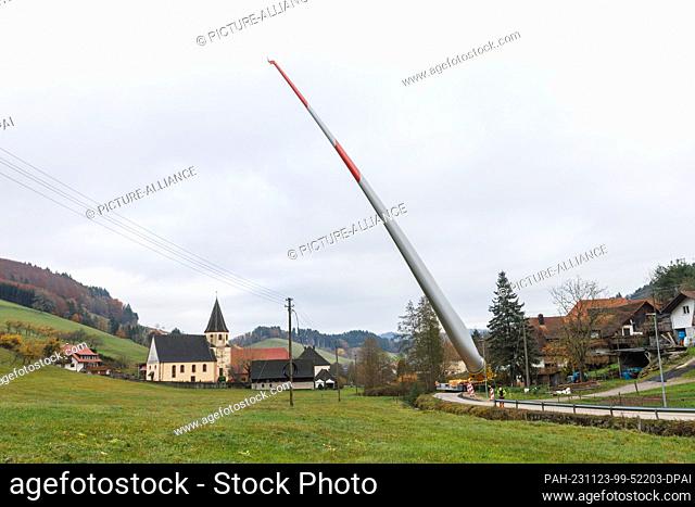 23 November 2023, Baden-Württemberg, Biberach: A wind turbine blade is mounted on a so-called self-propelled transporter and is being transported through the...