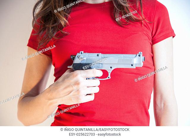 detail close up of woman with red tee shirt with a plastic toy silver false pistol gun in her hand