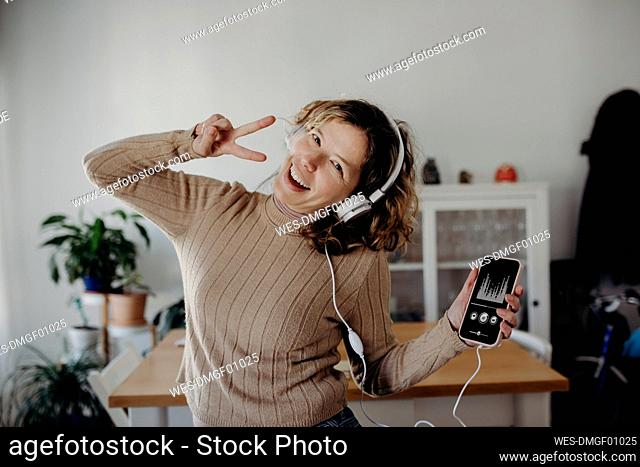 Carefree woman wearing headphones enjoying music and dancing at home