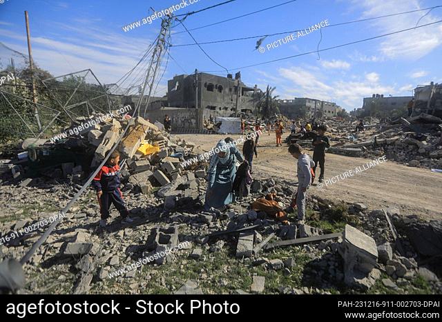 16 December 2023, Palestinian Territories, Rafah: Palestinians search for their belongings between the debris of destroyed buildings following the Israeli...