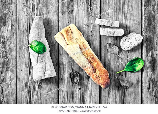 black end white. noir. appetizing ciabatta and basil on a wooden table. rustic style. Sliced with pieces for a bruschette. top view. copy space