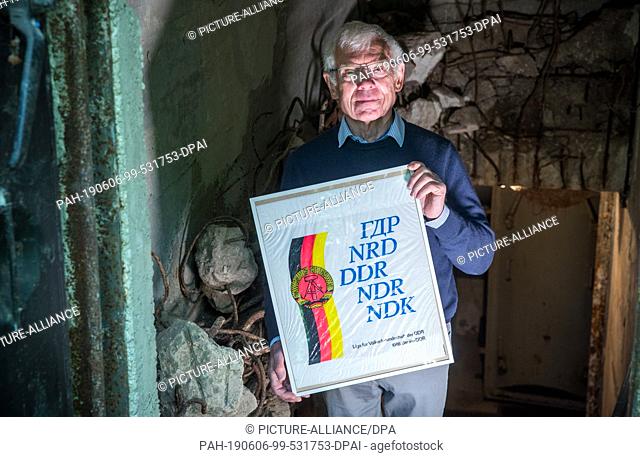 04 June 2019, Mecklenburg-Western Pomerania, Zurow: Dieter Luchs, collector of GDR shopping bags, holds a picture frame with a plastic bag of the League for...
