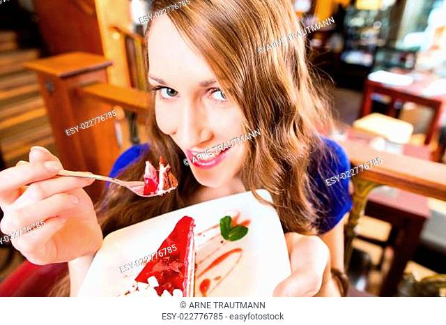 Young woman eating fruit cake at cafe or bakery