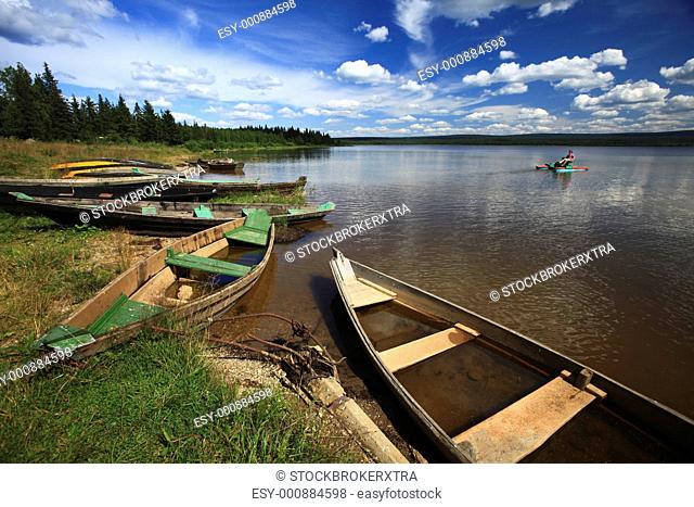 Image of lake with some boats on the shore under cloudy sky