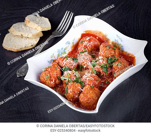 Bowl with meatballs in tomato sauce seasoned with fresh parsley and parmesan cheese