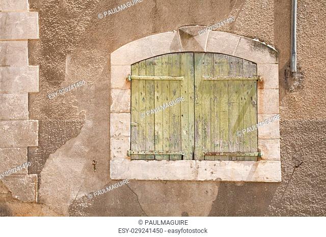Detail of an ancient stone wall in France with a traditional shuttered window