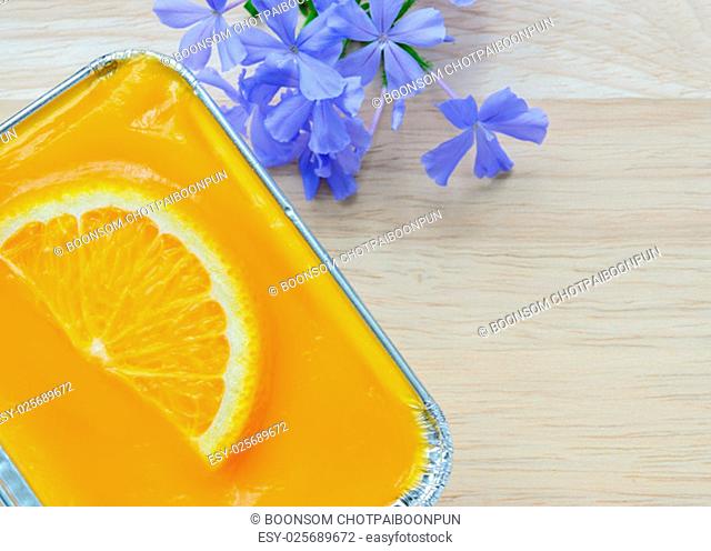 Orange soft cake with sliced orange fruit in aluminum foil tray on wooden background