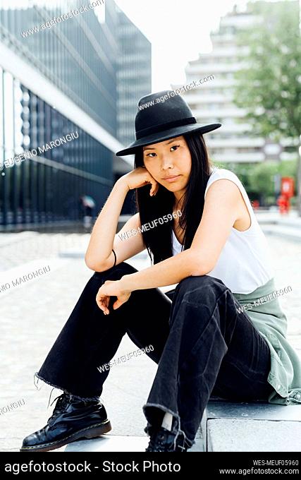 Beautiful young woman wearing hat sitting on steps