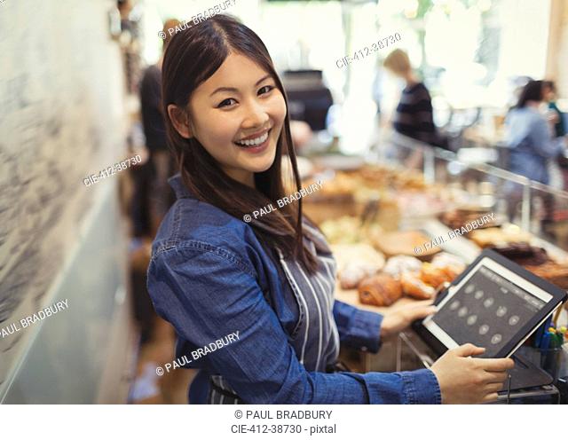Portrait smiling, confident female cashier at cash register in cafe