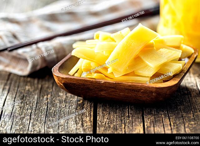 Sliced canned bamboo shoots in wooden bowl on wooden table