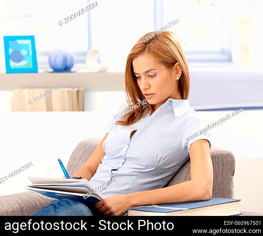 College student studying at home, sitting in armchair