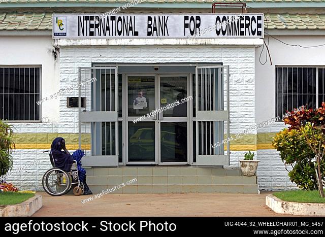 Old woman in wheelchair waits alone outside bank with no special access Bakau The Gambia