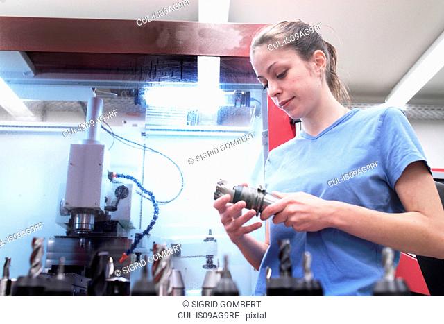 Female engineer checking tool in workshop