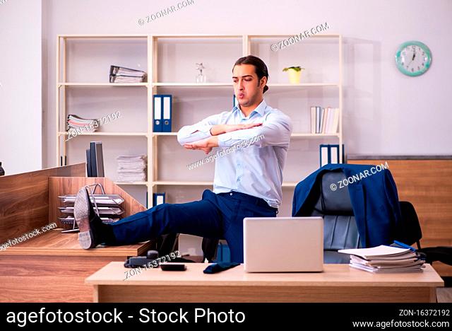 Young employee doing physical exercises at workplace