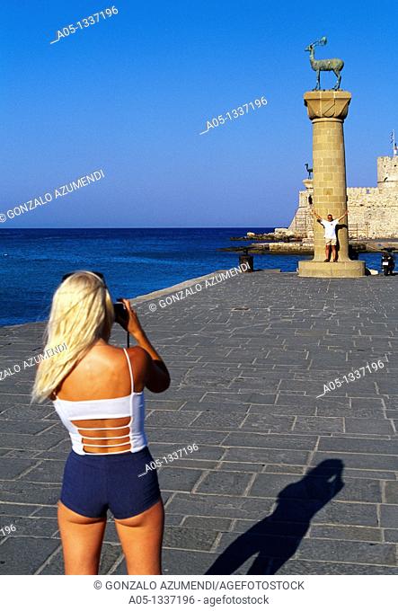 Girl Takind pictures to stag column  Mandraki Harbour  Rhodes City, Rhodes Island, Greece