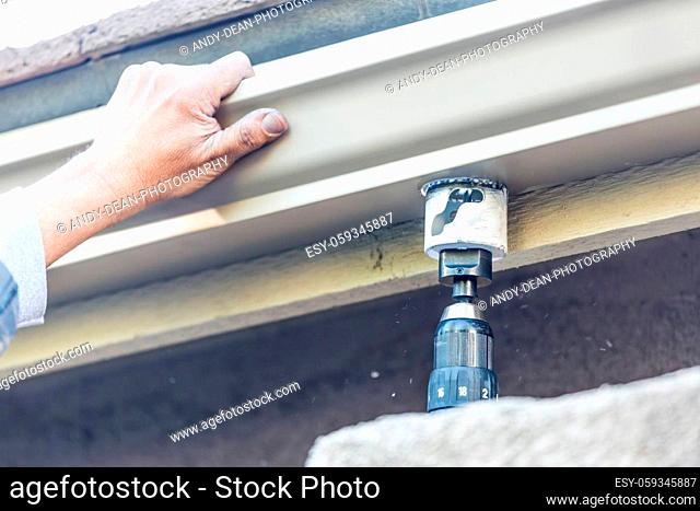 Worker Attaching Aluminum Rain Gutter to Fascia of House