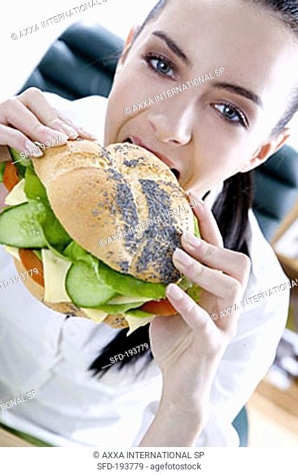 Businesswoman biting into a filled poppy seed roll (3)