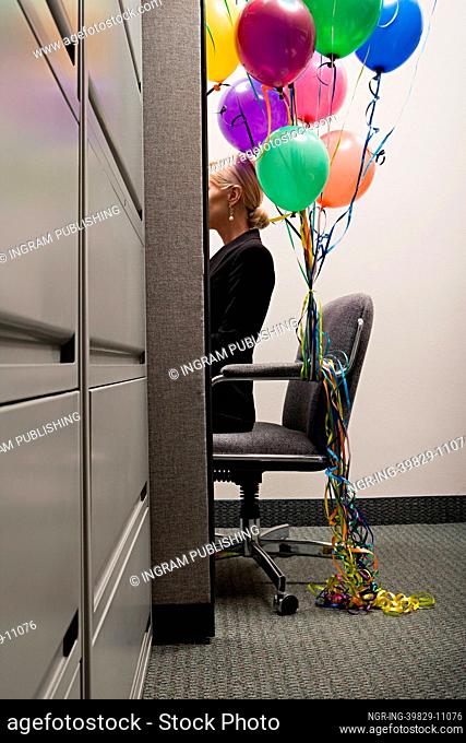 Businesswoman sat with bunch of balloons