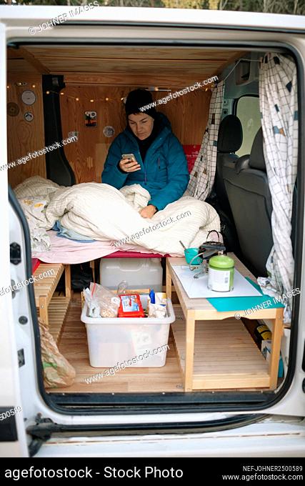Woman in camper van using cell phone