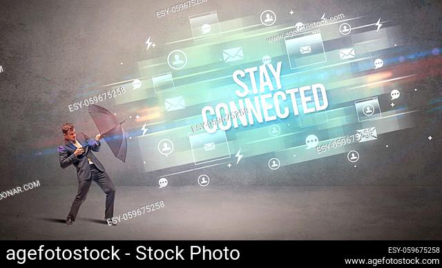 Handsome businessman defending with umbrella from STAY CONNECTED inscription, new age media concept