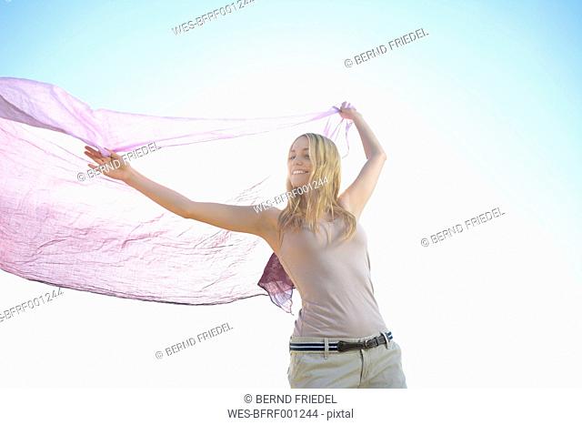 Woman holding cloth in front of sky
