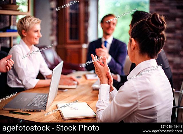 Selective Focus Of Businesswoman's Back Sitting At The Meeting. Blurred Image Of Businessmen Discussing Working Issues