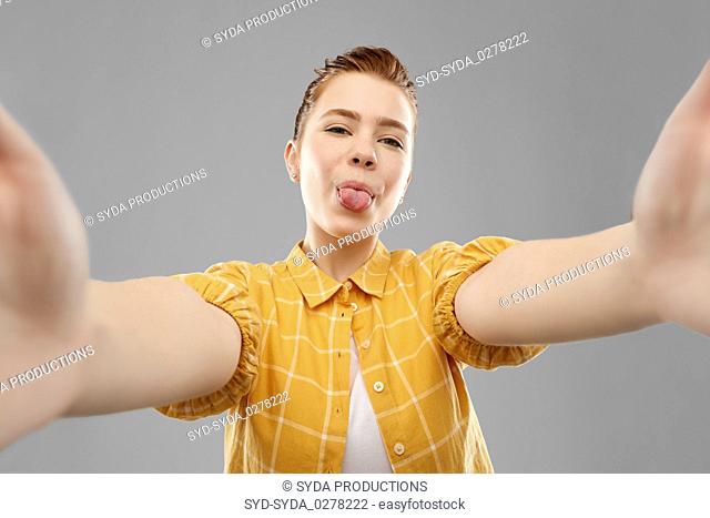 red haired teenage girl taking selfie with tongue