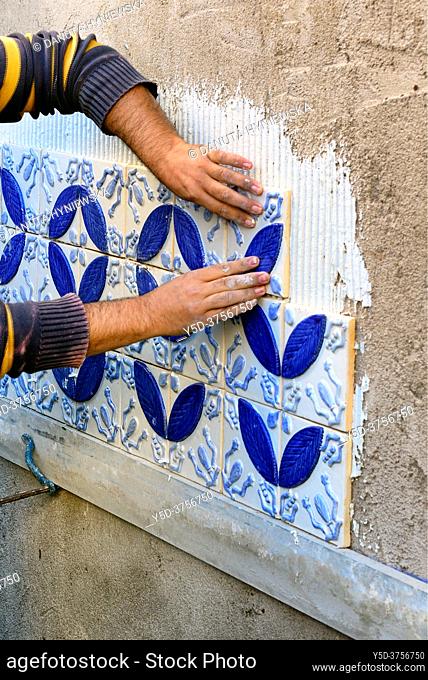 A builder, tiler placing azulejos on exterior wall, Algarve, Portugal, Europe