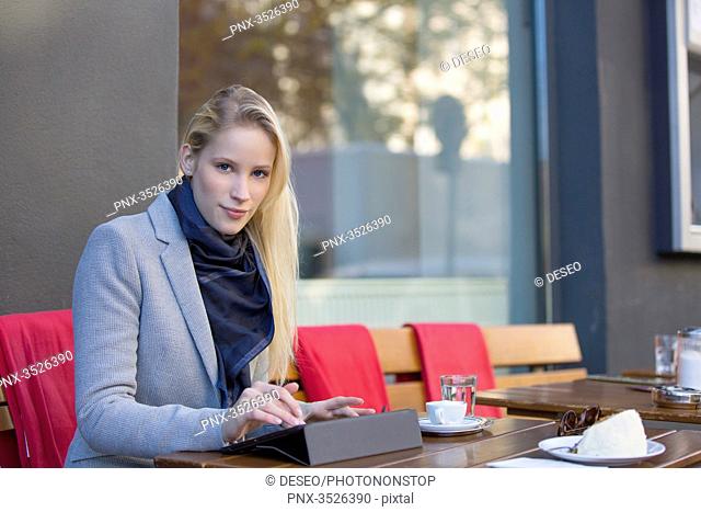 Pretty blonde woman with tablet in a Cafe looking at camera