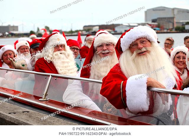 22 July 2019, Denmark, Kopenhagen: Santa Clauses are sitting in an excursion boat. Dozens of white-bearded men and Christmas women wearing red and white striped...
