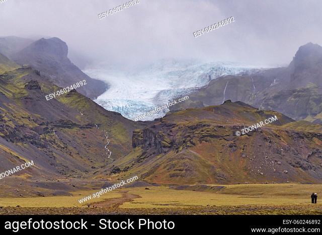 a group of people, looking towards the highlands and the glacier and the moss covered mountains in Iceland