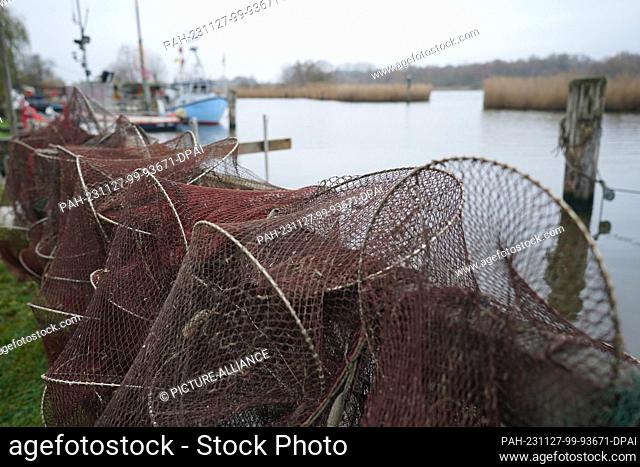 27 November 2023, Schleswig-Holstein, Lübeck: Fishing boats, nets and traps lie on a jetty in the small fishing village of Gothmund on the River Trave