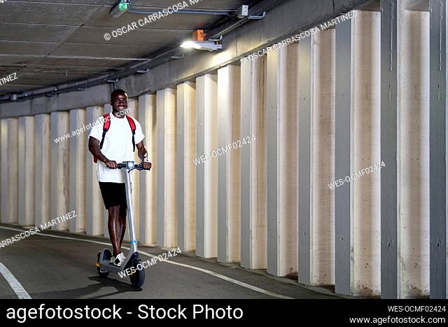 Young man riding electric scooter in tunnel