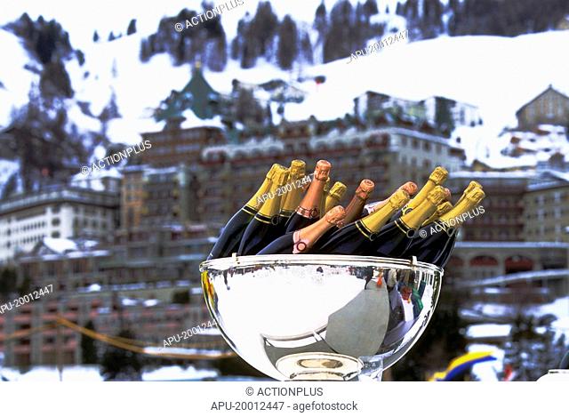 Bottles of champagne in ice bucket awaiting winners of Ice Polo Match against large hotel in background