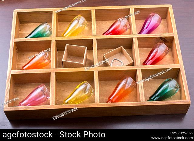 Colorful small bottles and small carton boxes in a wooden box in the view