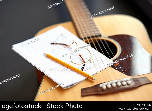 close up of guitar, music book, pencil and glasses