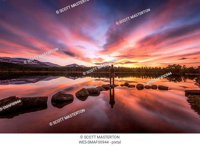 United Kingdom, Scotland, Highlands, Cairngorms National Park, Loch Morlich, sunset, hiker standing on stone