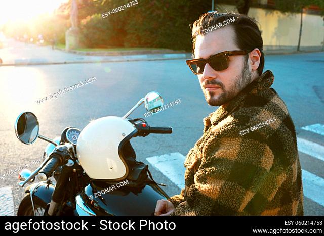Bearded biker man on motor bike posing outdoors at the city streets. High quality photo