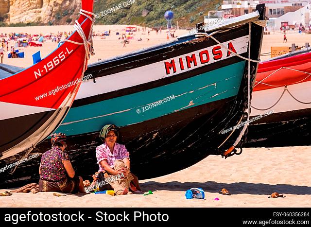 NAZARÉ, PORTUGAL - JUNE, 10 2020: Fishermen's Woman Selling Dry Fish in the Beach - Traditional Crafts in a Popular Resort in West Region