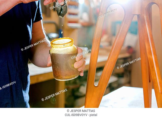 Craftsman polishing wooden stool with oil finish