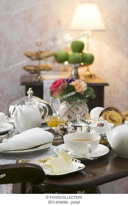 Tea things and butter dish on attractively laid table