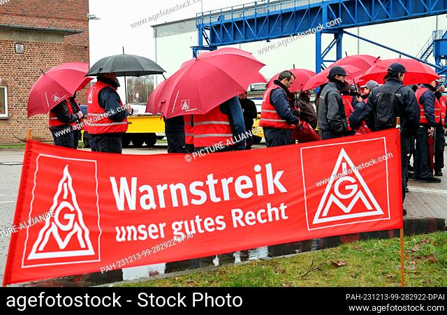 13 December 2023, Mecklenburg-Western Pomerania, Rostock: Employees of wind turbine manufacturer Nordex Energy stand behind a banner reading ""Warning strike -...