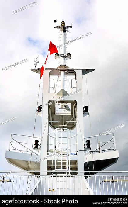 White ship's navigation tower mast with Canadian flag and cloudy sky